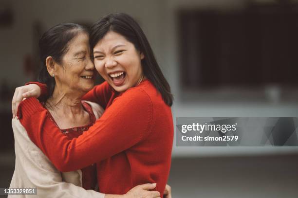 eine asiatische großmutter umarmt ihre enkelin mit liebe - alter wunsch fürs neue jahr stock-fotos und bilder