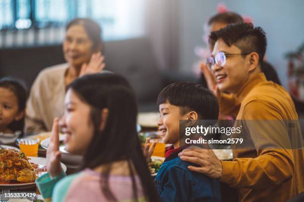 fröhliche asiatische familie mit online-gruß zum chinesischen neujahr und treffen mit verwandten per videoanruf zu hause während des wiedersehensessens - chinese new year food stock-fotos und bilder