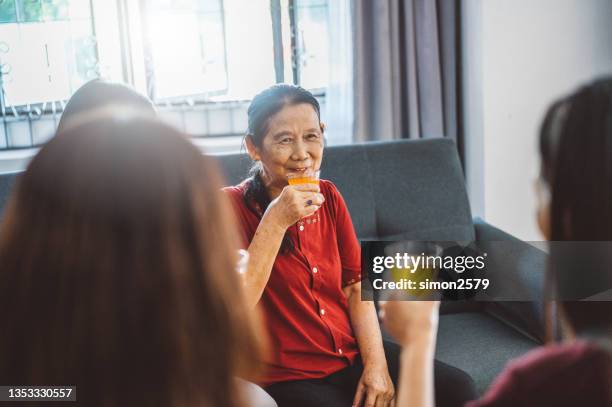 joyful asian family celebrating chinese new year and toasting orange juice at living room - shared prosperity stock pictures, royalty-free photos & images