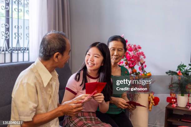 teenager-enkelin erhält roten umschlag von großeltern während des chinesischen neujahrsfestes - chinese new year red envelope stock-fotos und bilder