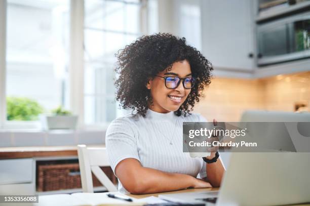 photo d’une jeune femme utilisant un ordinateur portable et prenant un café tout en travaillant à partir de - kitchen internet photos et images de collection