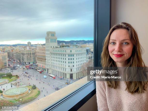 young woman looking out the window - plaza de catalunya foto e immagini stock