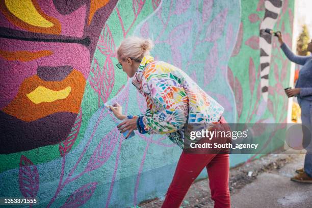 künstlerinnen malen an gebäudewand - straßenmaler stock-fotos und bilder