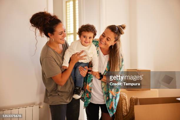 a female lgbt couple with a child moves to a new home. - lesbische stockfoto's en -beelden
