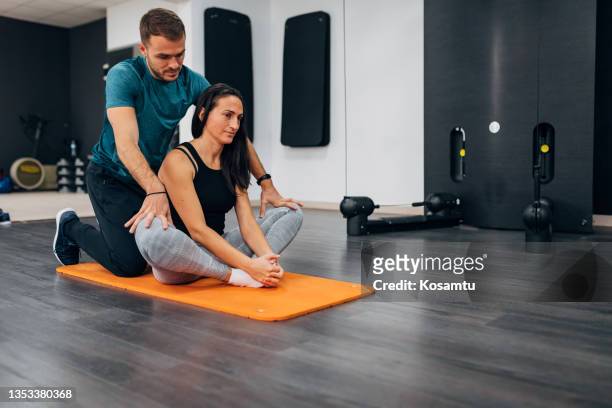 after training, the female athlete does stretching. she stretches her groin, and the male personal trainer pushes her knees. - male crotch stock pictures, royalty-free photos & images