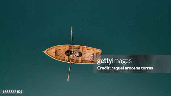 Drone view of a couple rowing a boat on a lake Drone view of a couple rowing a boat on a lake