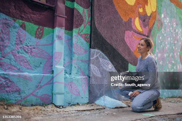 pintura en aerosol de artista femenina en la pared del edificio - mural fotografías e imágenes de stock