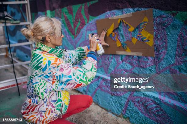 straßenkünstler sprühen malerei an gebäudewand - graffiti artist stock-fotos und bilder