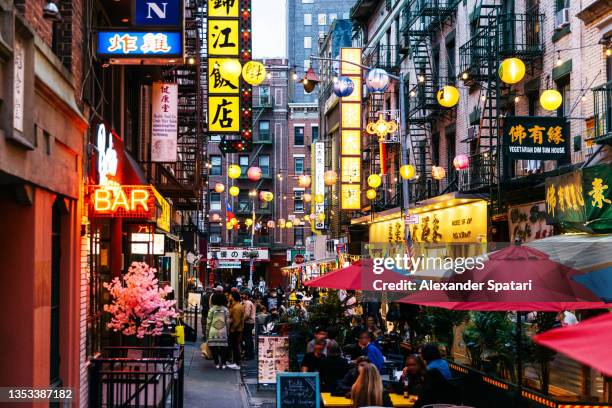 crowded illuminated street with restaurants in bars in chinatown, new york city, usa - chinese language fotografías e imágenes de stock