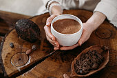 Person giving ceremonial cacao in cup. chocolate drink top view