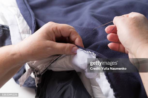 adult woman mending clothing, close-up of hands, economic consumption. - mani fili foto e immagini stock