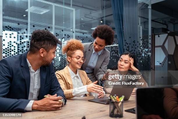 motivated multiracial group of business people, working on a laptop from board room - meeting candid office suit stock pictures, royalty-free photos & images