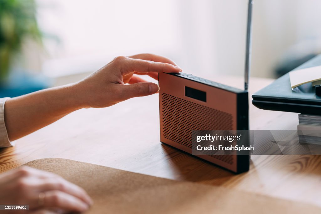 Primer plano de la mano de la mujer ajustando el volumen del sonido en la radio