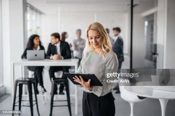 business woman working on her tablet in a bright office - 40 50 business woman stock pictures, royalty-free photos & images