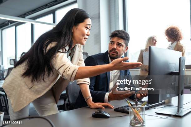 enttäuschte asiatische geschäftsfrau, die sich mit ihrem gemischtrassigen männlichen kollegen im büro streitet - business confuse conflict stock-fotos und bilder