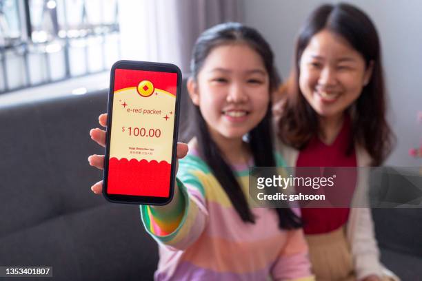 teenage girl receicing digital red envelope from parent during chinese new year - heritage festival presented stock pictures, royalty-free photos & images