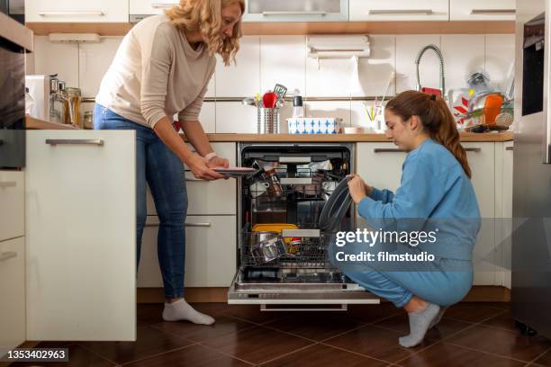 mother and daughter unloading dishwasher - loading dishwasher stock pictures, royalty-free photos & images