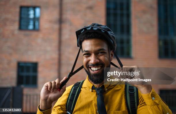 portrait of man commuter putting on cycling helmet and looking at camera, sustainable lifestyle. - cycling helmet stock-fotos und bilder