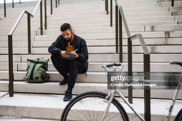 portrait of man commuter with bicycle using tablet in city. - bike ipad stock pictures, royalty-free photos & images