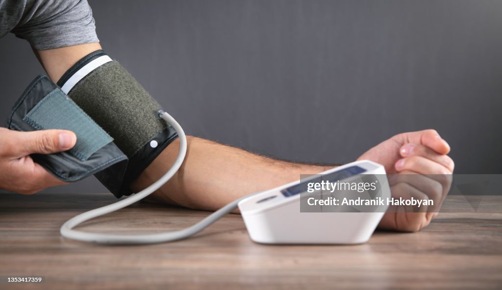 Hombre caucásico midiendo su presión arterial en casa.