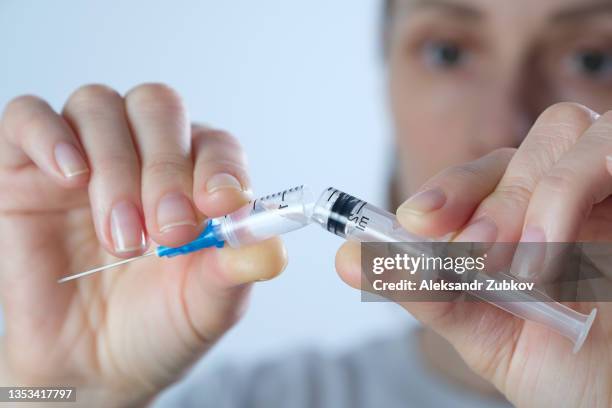 a broken syringe for injection of the covid 19 vaccine in the hands of a woman, a medical worker. movement against vaccination, refusal of it. the girl refused to be vaccinated. anti-immunization campaign. the concept of freedom of choice and human rights - petizione foto e immagini stock