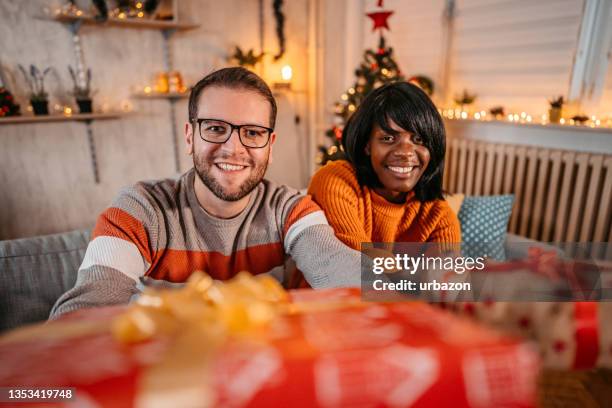 man and woman giving presents to person behind camera - christmas gift exchange stock pictures, royalty-free photos & images