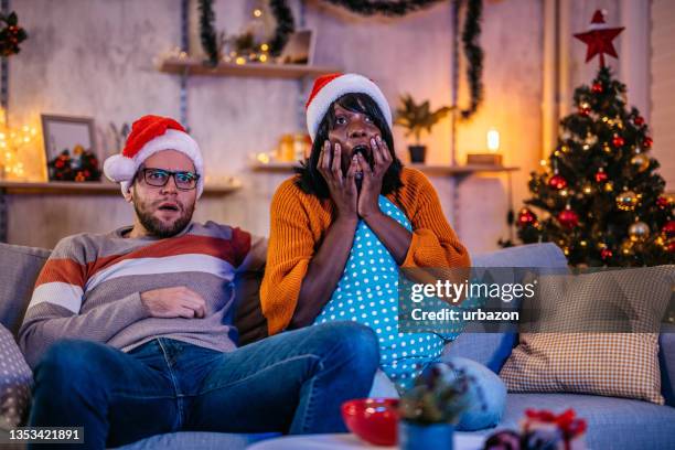 scared couple watching horror movie at christmas - christmas movie stock pictures, royalty-free photos & images