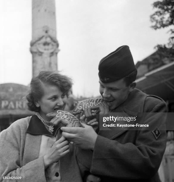 Jeune couple mangeant du pain d'épice à la foire du Trône, le 13 avril 1952, à Paris.