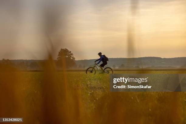 cyclist riding bicycle on agricultural field - cross country cycling stock pictures, royalty-free photos & images