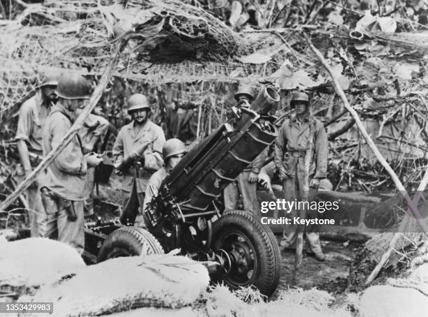 Camouflaged gun crew from the 11th Marines artillery battalion,1st Marine Division of the United States Marine Corps prepare to fire a barrage from a...