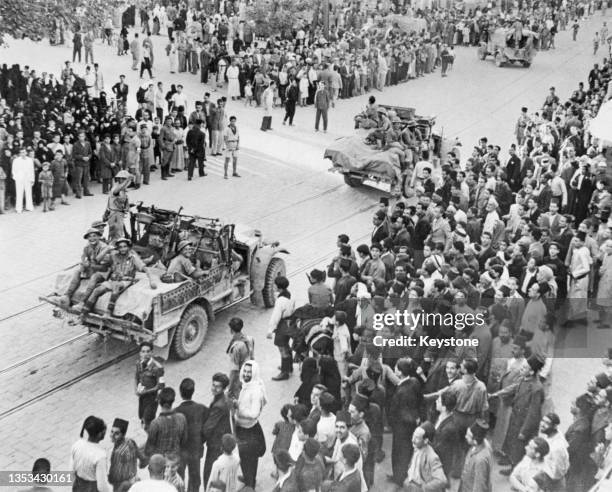 The civilian population looks on as troops from the Australian I Corps and Gentforce consisting of Indian, Free French and British brigades drive...