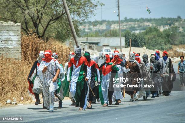 View of a group of hooded and masked Pro-Palestinian activists, some dressed in the colors of the Palestinian flag, as they march along a road during...