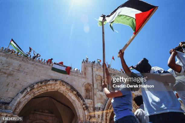 Low-angle view of a group of Pro-Palestinian activists, as they wave Palestinian flags outside walls of the Old City, during the First Intifada,...