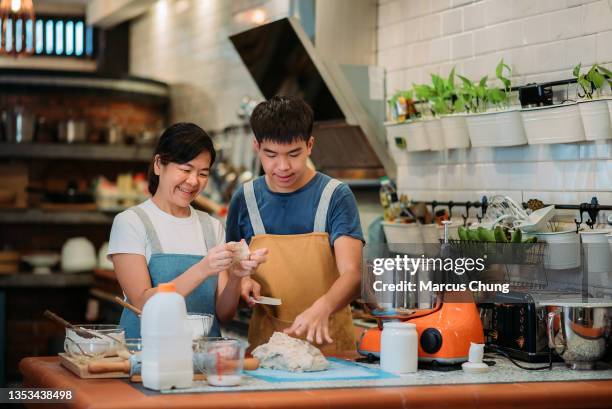 asian chinese smiling baker mother and son preparing dough togethers in the kitchen - malaysia father and son stockfoto's en -beelden