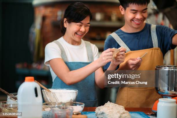 asiatisch-chinesische lächelnde bäckermutter und sohn bereiten gemeinsam teig in der küche zu - 2 people back asian stock-fotos und bilder