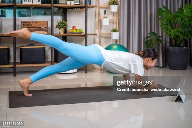 girl training at home, doing plank and watching videos on laptop, training in living room - pilates abstract stock pictures, royalty-free photos & images