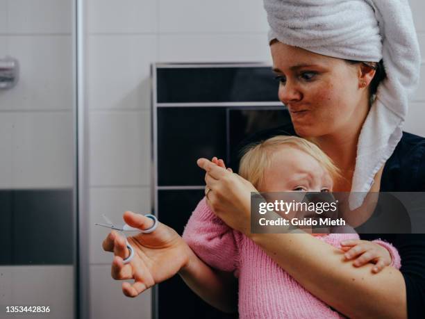 angry mother trying to cut finger nails of her little daughter. - baby head in hands stock pictures, royalty-free photos & images