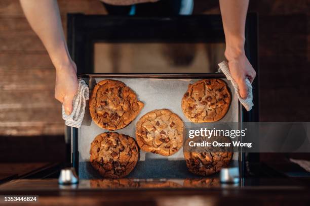 high angle view of female hands taking out freshly baked cookies from the oven - bakplåt bildbanksfoton och bilder