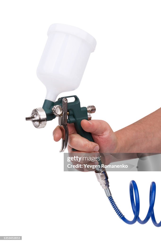 Paint spray gun in hand isolated on white background