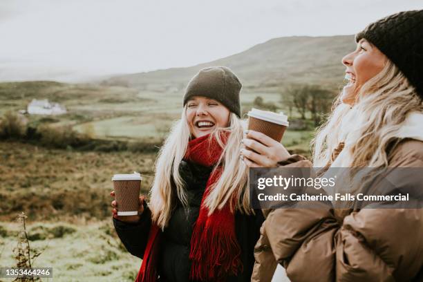 two beautiful young woman enjoy the great outdoors, dressed for winter, and drinking takeaway coffees - catherine falls stock pictures, royalty-free photos & images
