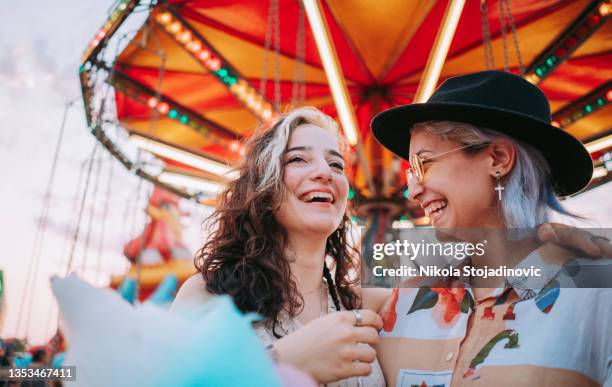 glückliche freundinnen machen gemeinsam spaß auf der kirmes - lgbtqi menschen stock-fotos und bilder