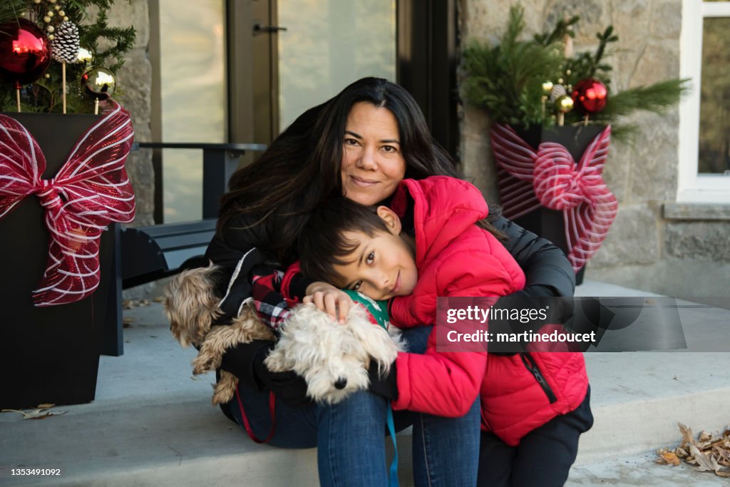 Retrato de la temporada navideña de madre, hijo y perros al aire libre.
