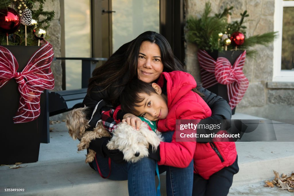 Holiday season portrait of mother, son and dogs outdoors.