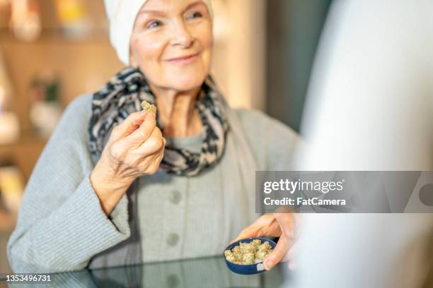 woman with cancer holding up cannabis product - cannabinoid stock pictures, royalty-free photos & images