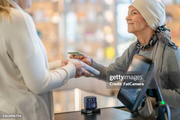 krebspatientin tippt auf ihre debitkarte für einen kauf - cannabis dispensary stock-fotos und bilder