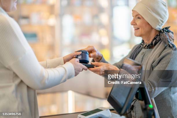 store clerk handing a customer her purchase - medical marijuana law stock pictures, royalty-free photos & images