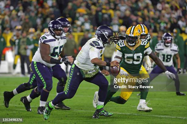Russell Wilson of the Seattle Seahawks is pursued by De'Vondre Campbell of the Green Bay Packers during a game at Lambeau Field on November 14, 2021...