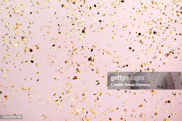 many festive golden confetti falling against pastel pink background. concept of new year or birthday celebration. perfect backdrop for your design - pink confetti stock pictures, royalty-free photos & images