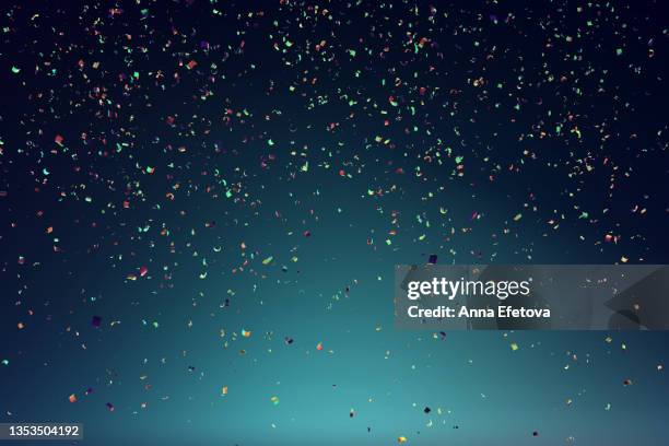 many festive multi colored confetti falling against blue background. concept of carnival or birthday celebration. perfect backdrop for your design - cumpleaños fotografías e imágenes de stock