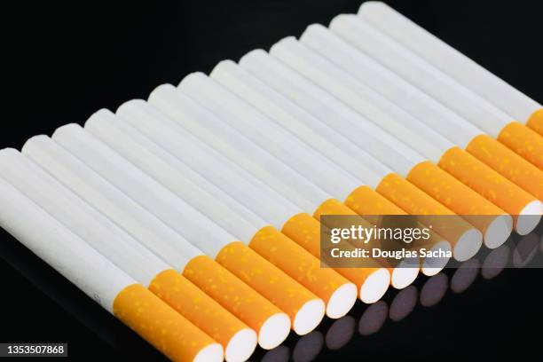 cigarettes in a pattern on black background - filtre de cigarette photos et images de collection
